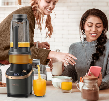 Kobiety korzystające z aplikacji z przepisami i inspiracjami kuchennymi, podczas gotowania z wykorzystaniem blendera z funkcją sokowir&oacute;wki Flip&Juice.