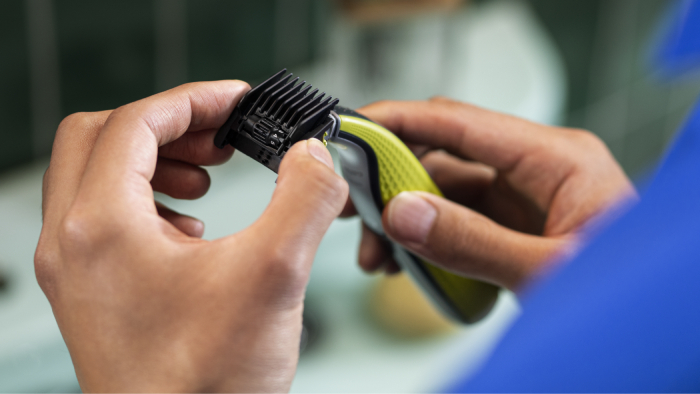 Plecy mężczyzny, kt&oacute;ry pochyla się nad zlewem, aby włożyć ręce pod bieżącą wodę. 