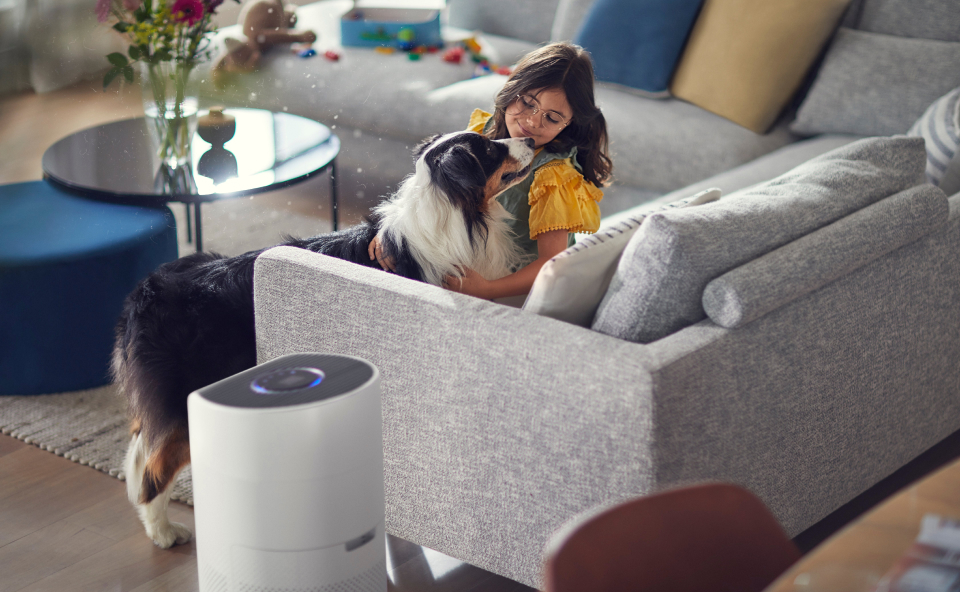 Dziewczynka bawi się z psem, a właczony oczyszczacz powietrza pochłania nieczystości