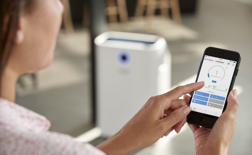 Kobieta włącza oczyszczacz powietrza w kuchni by pozbyć się nieprzyjemnych zapach&oacute;w.