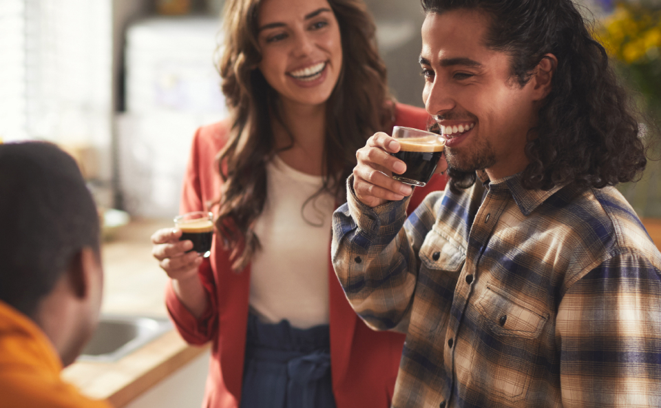 Grupa ludzi pije czarną kawę z ekspresu, podczas rozmowy