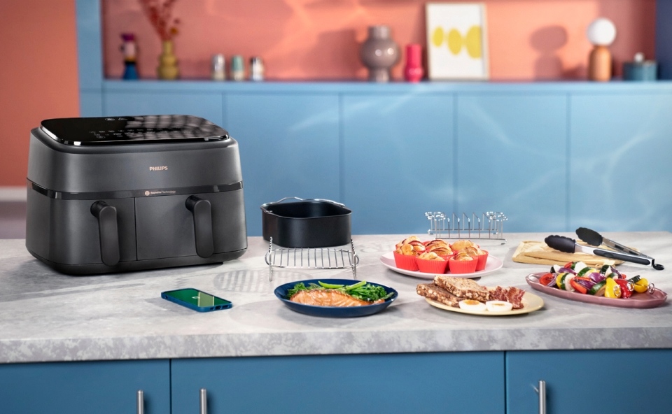 Kobieta przygotowuje frytki w airfryerze. Otwiera szufladę sprawdzając gotowość dania.