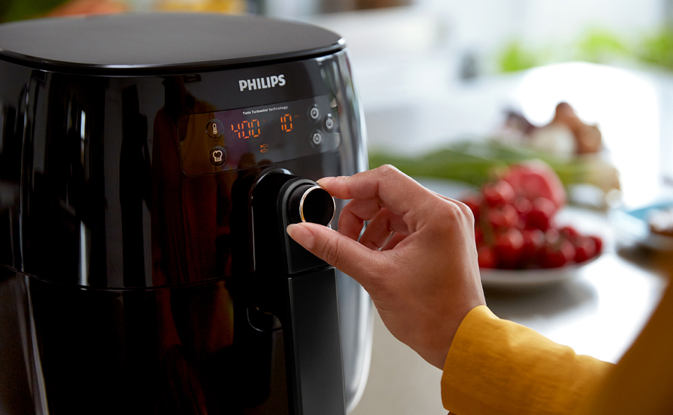 Kobieta ustawia temperaturę i czas pieczenia w airfryerze