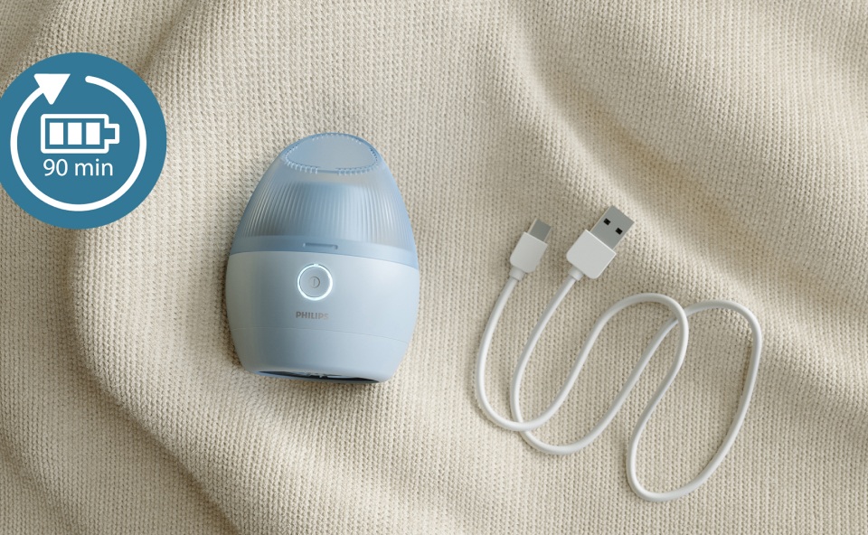 Położona na swetrze golarka do ubrań obok niej kabel USB do ładowania.