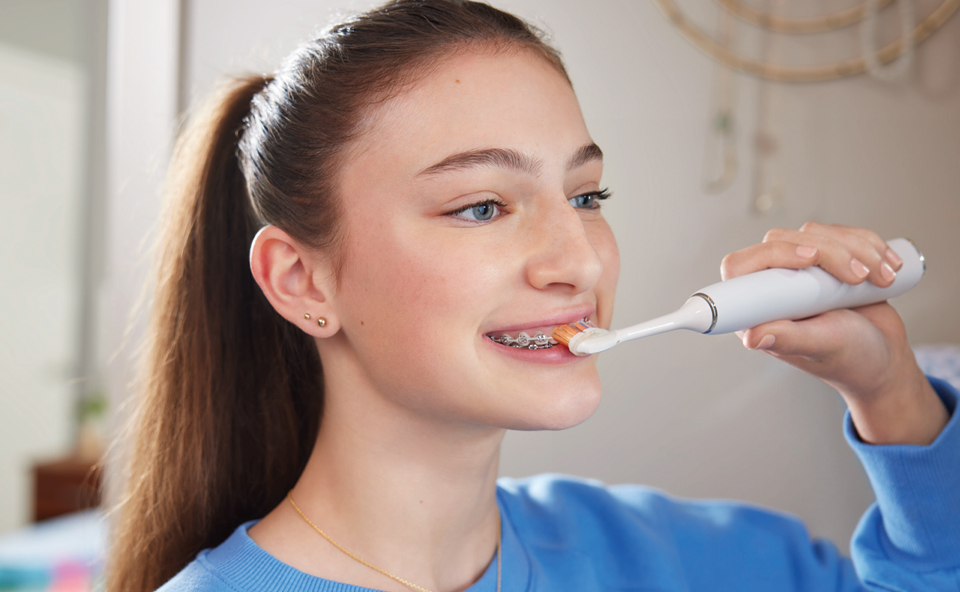 Pacjent ortodontyczny myjący zęby szczoteczką soniczną Philips.