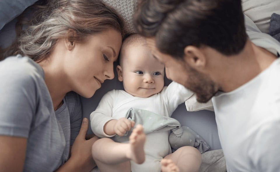 Niemowlak z-rodzicami w ł&oacute;żku.