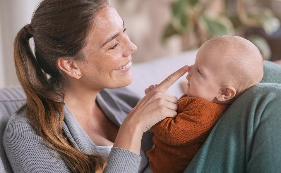 Uśmiechnięte niemowlę na rękach matki