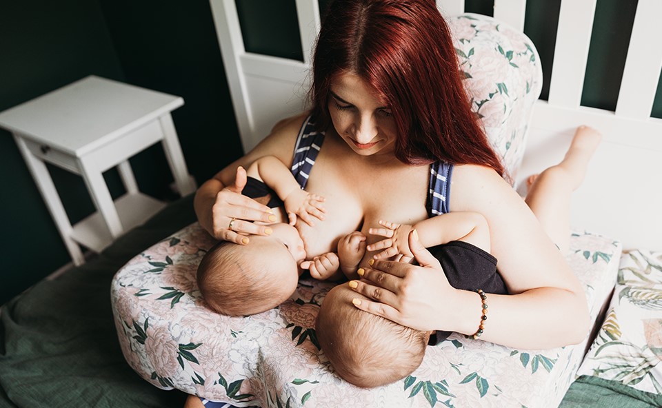 Kobieta karmiąca dw&oacute;jkę dzieci.