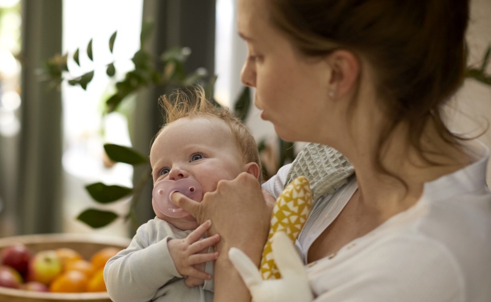 Mama z dzieckiem, dziecko ze smoczkiem w buzi.