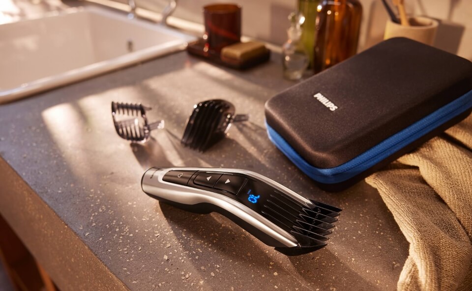 Trymer Philips z nasadkami leżący na blacie w łazience obok etui.