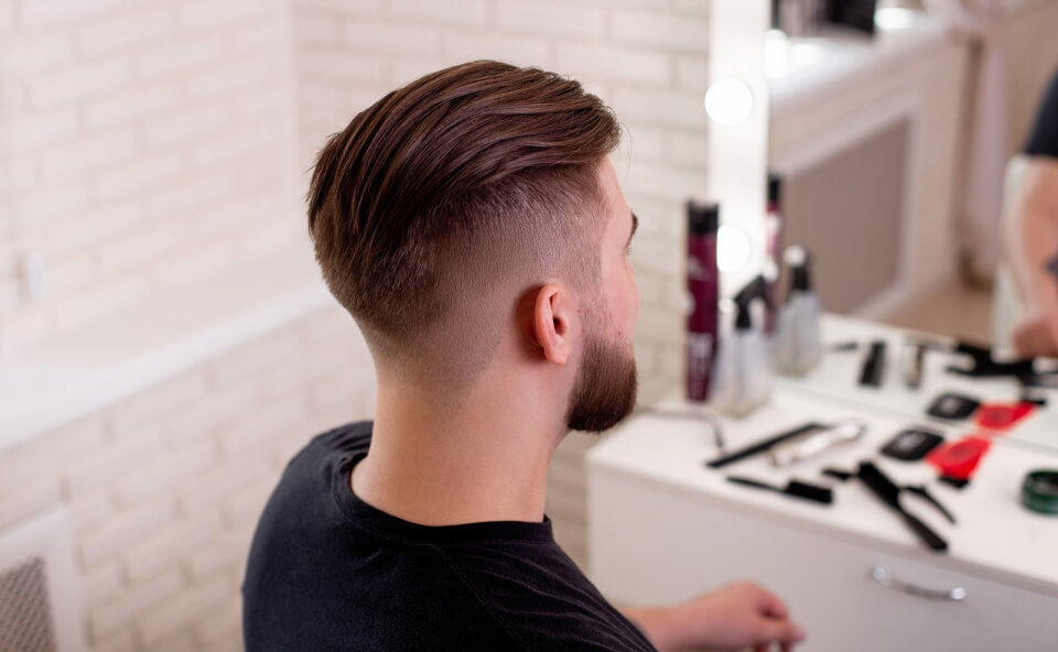 Mężczyzna z fryzurą undercut siedzący przy stanowisku w salonie fryzjerskim