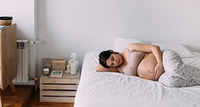 Ciężarna kobieta odpoczywająca na ł&oacute;żku